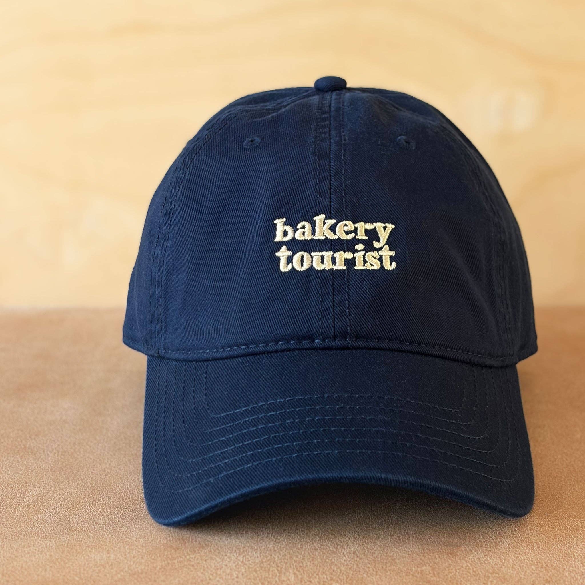 Relaxed navy cotton baseball cap by Alphabet Bags with Bakery Tourist embroidery.