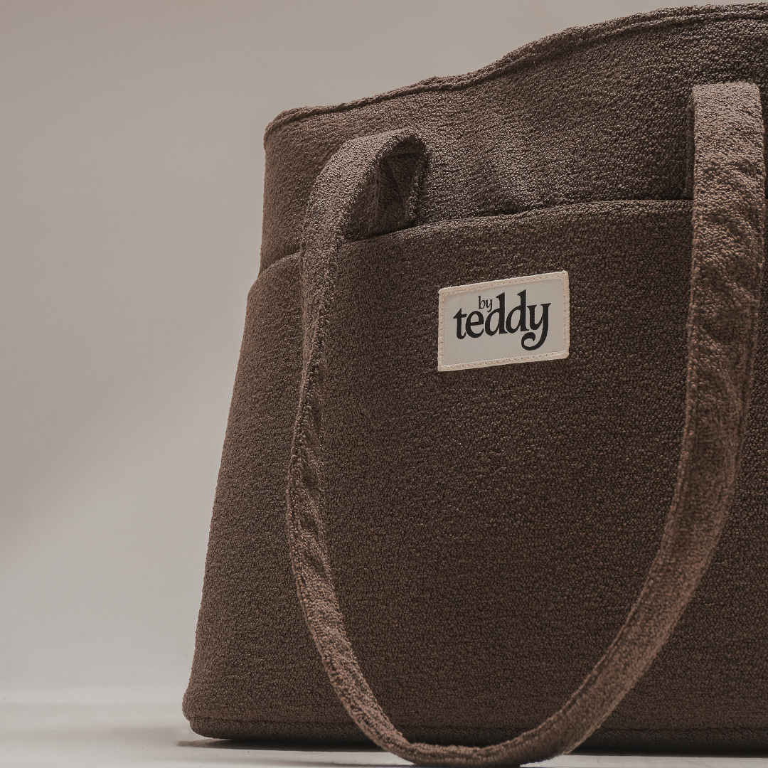 Brown tote bag with 'the teddy' label on a light gray background