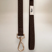 Brown dog leash with metal clip and visible brand label on a light gray background
