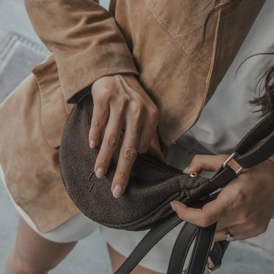 Person holding a brown leather bag with a blurred background