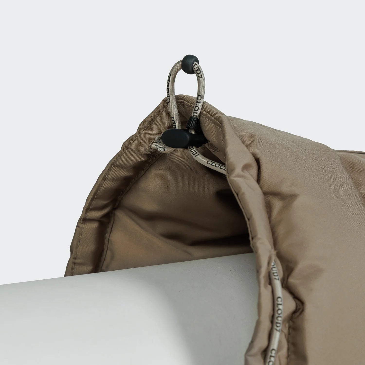 Close-up of a beige backpack with a carabiner on a light gray background
