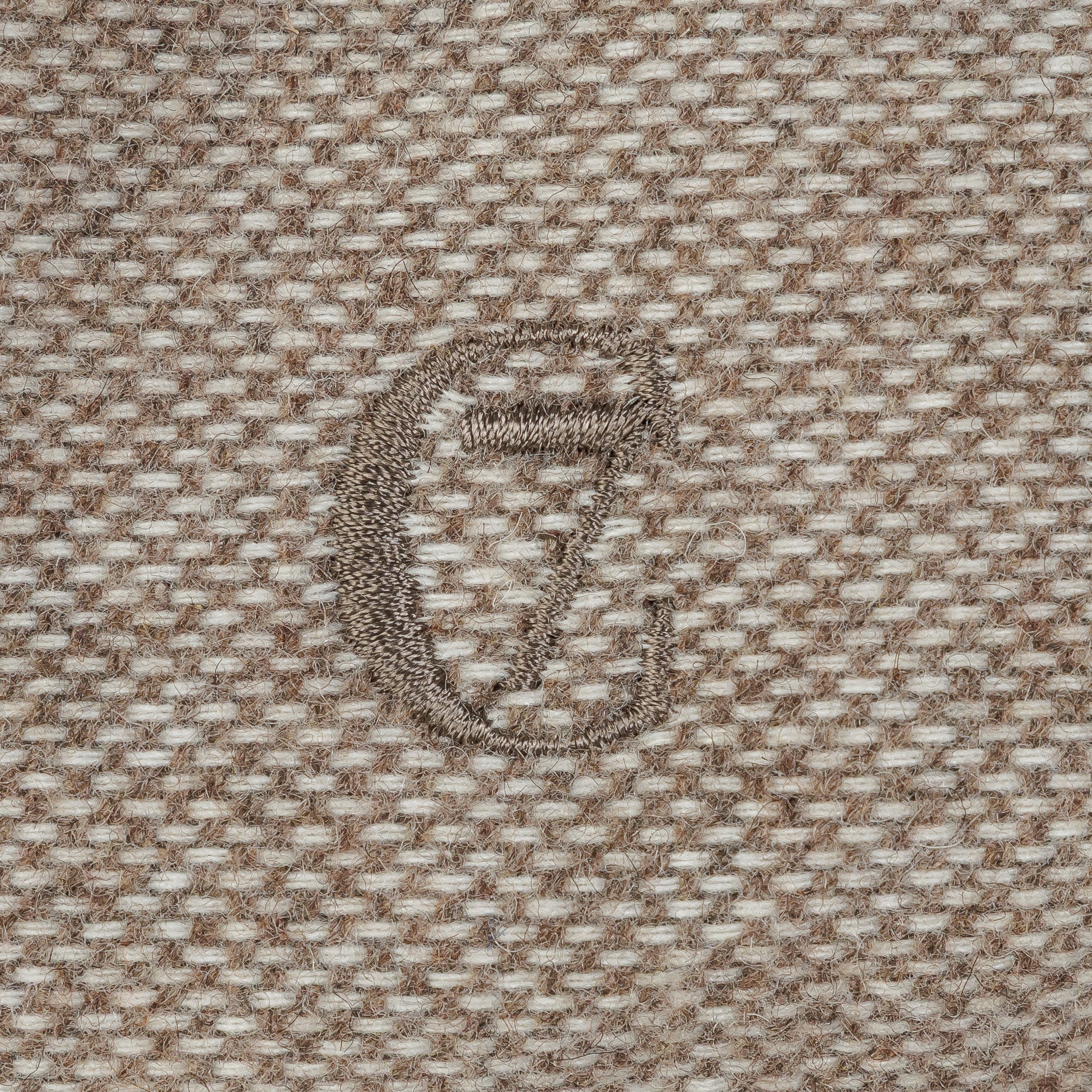 Close-up of a textured fabric with a logo in the center.