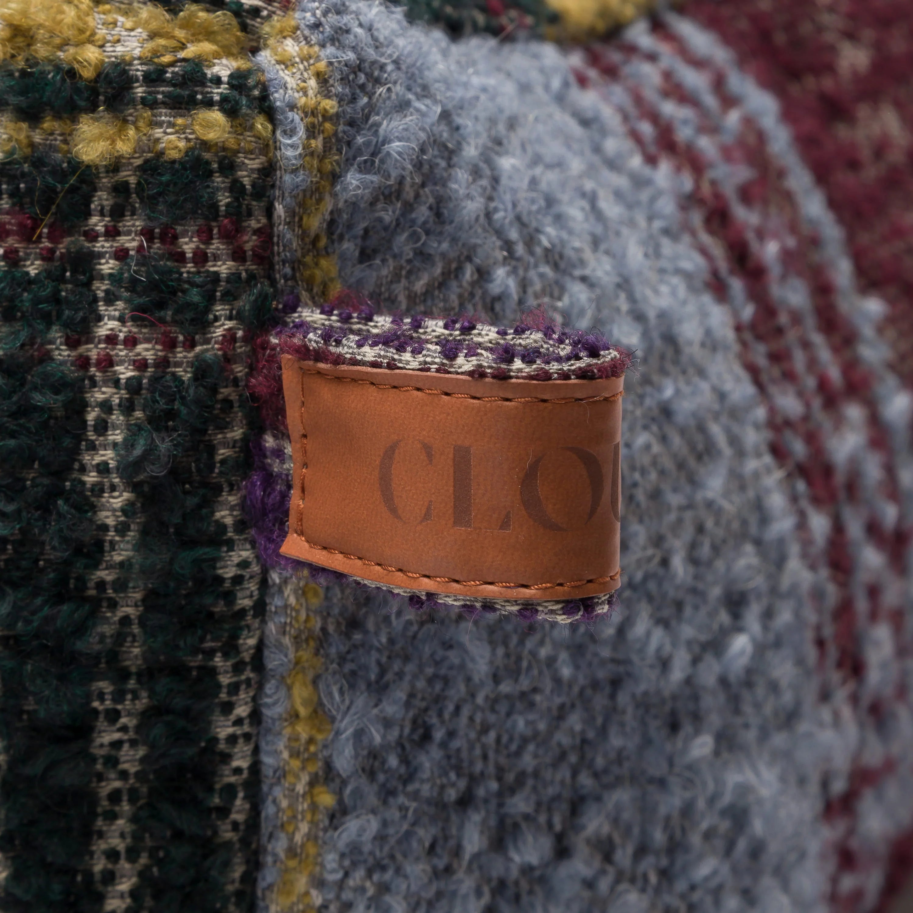Close-up of a textured fabric with a brown leather tag displaying 'CLO'.