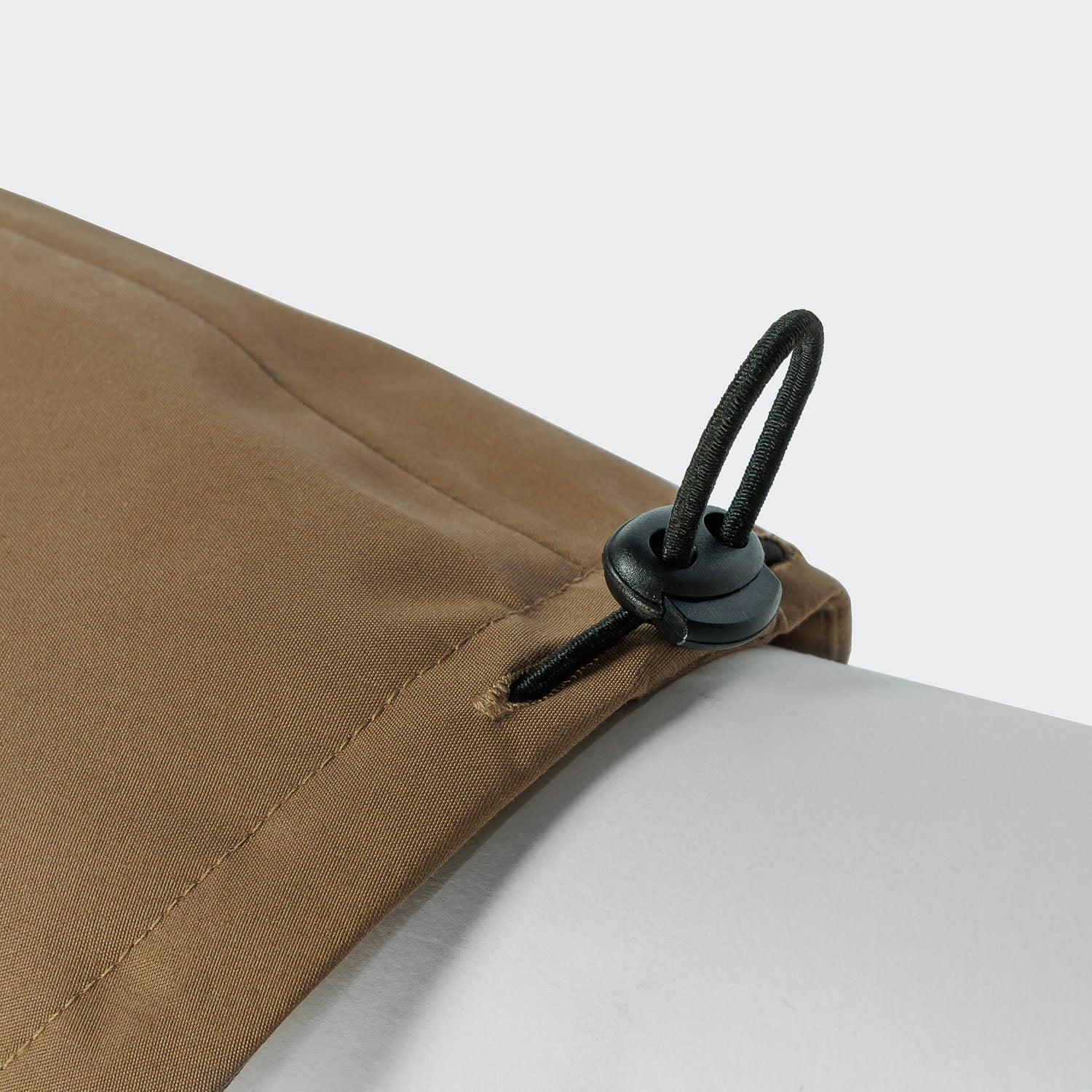 Close-up of a brown fabric with a black cord lock on a white background