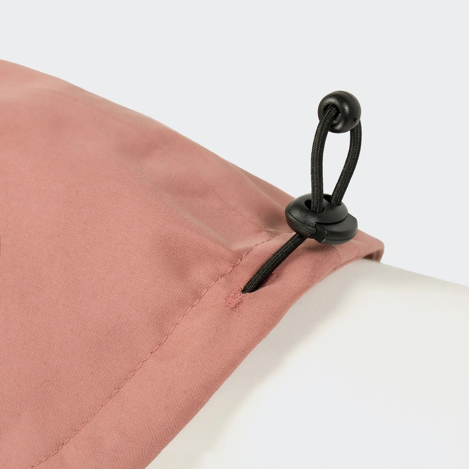 Close-up of a pink fabric with a black cord tie on a white background