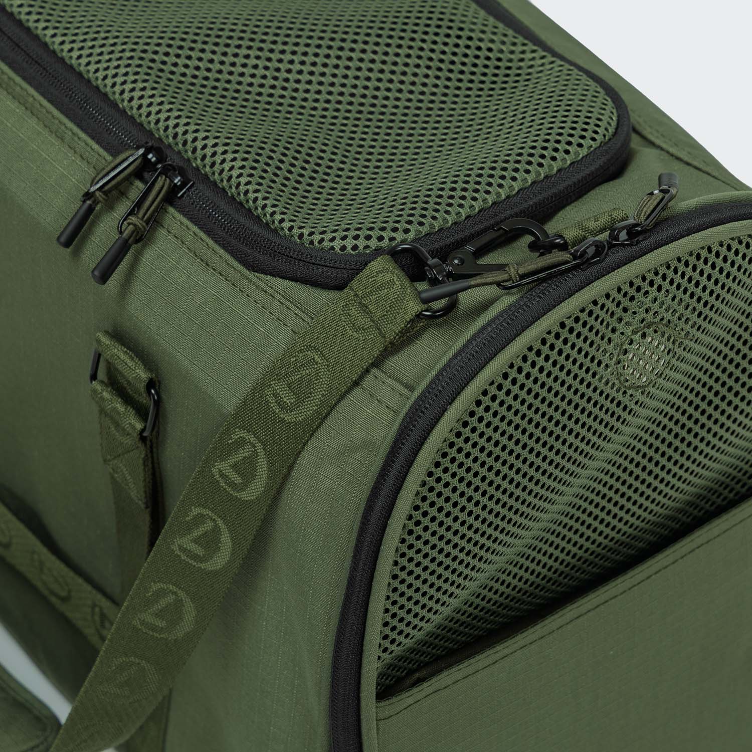Green pet carrier with mesh sides and zippers on a light gray background