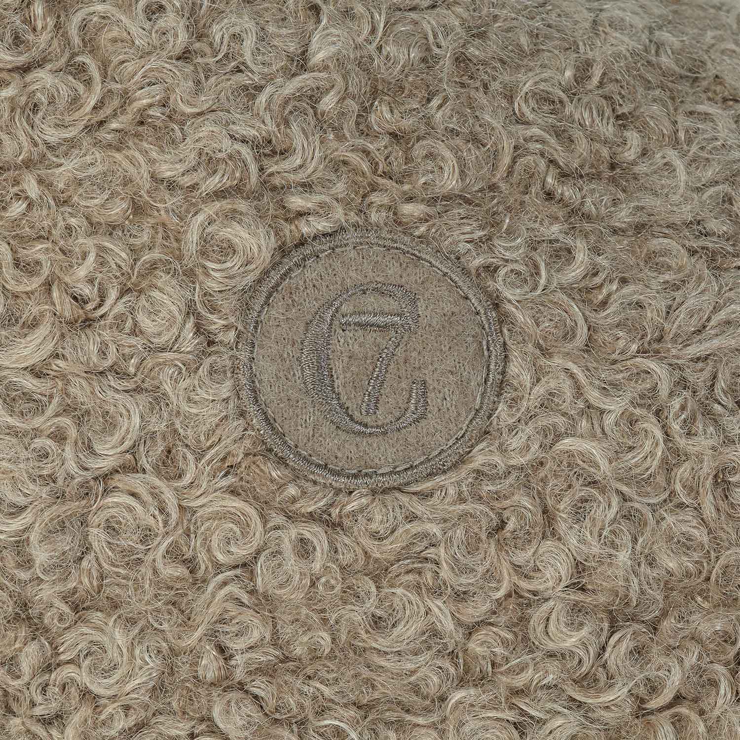 Textured fabric with a circular emblem featuring a letter 'L' on a beige background