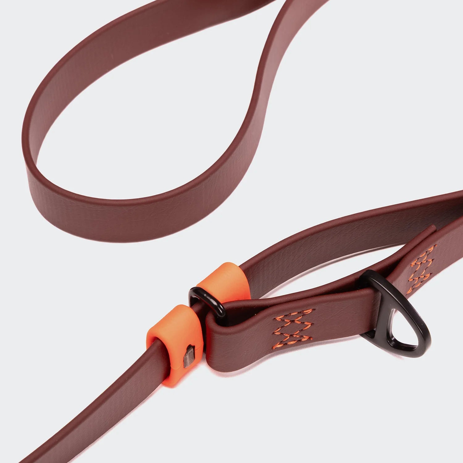 Brown dog leash with an orange clip on a light gray background
