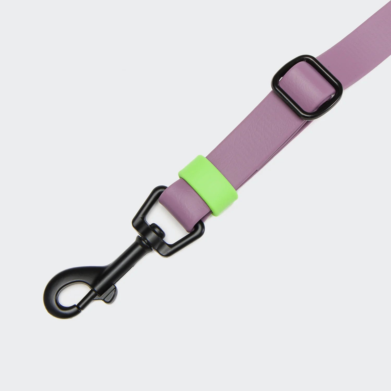 Purple dog leash with a green handle and black clip on a light gray background