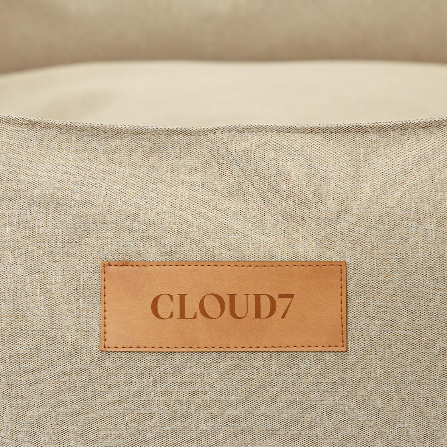 Close-up of a beige fabric surface with a 'Cloud7' leather label.