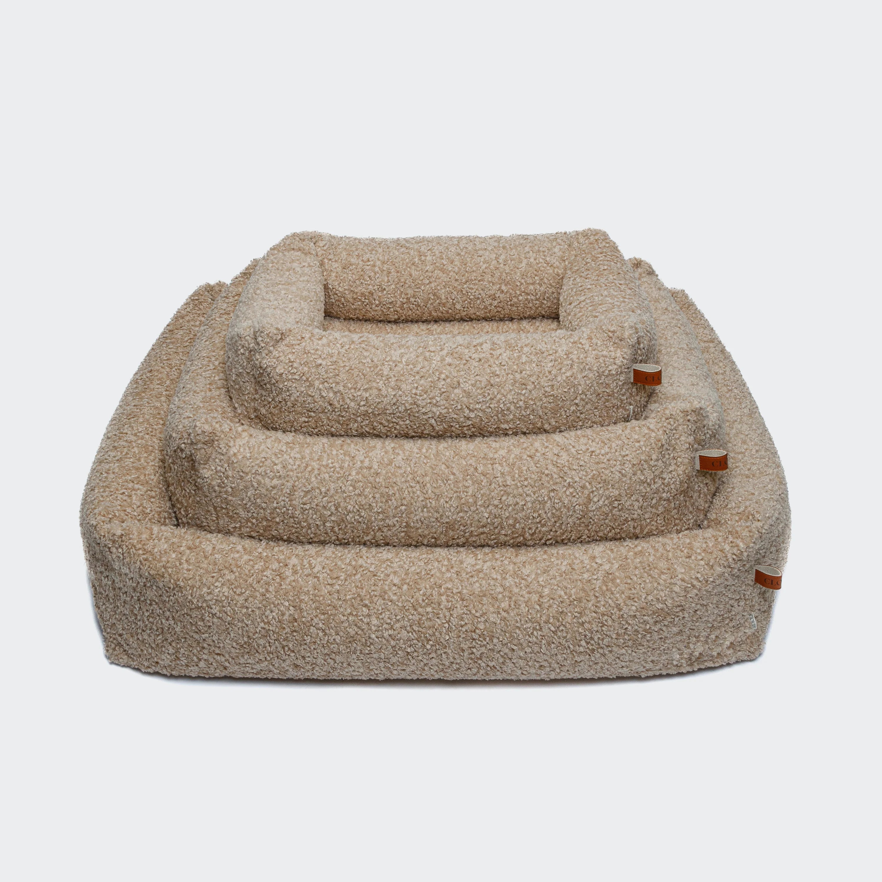Luxury cream dog bed with textured bouclé finish and comfortable bolster design.