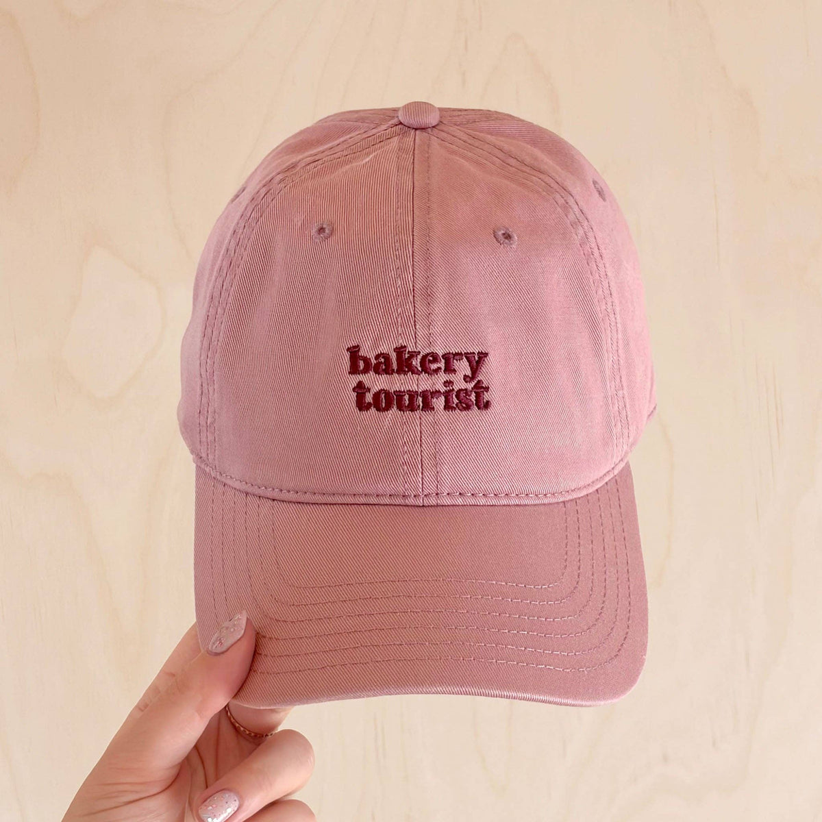 Cocoa brown Bakery Tourist baseball cap with pale pink embroidered lettering.