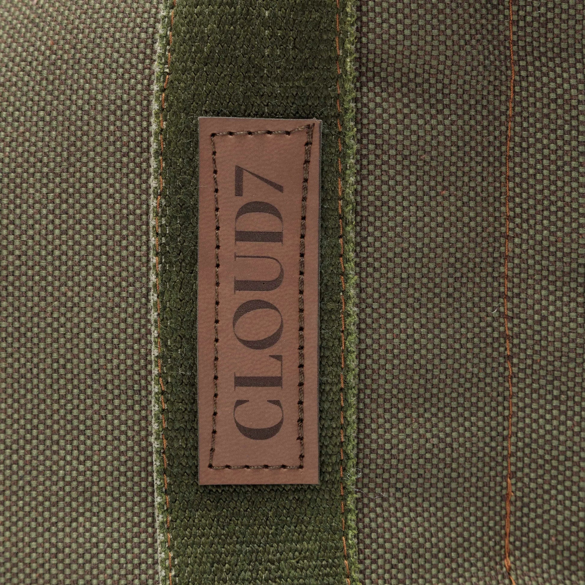 Close-up of a brown leather label with 'CLOUD7' on a textured fabric background