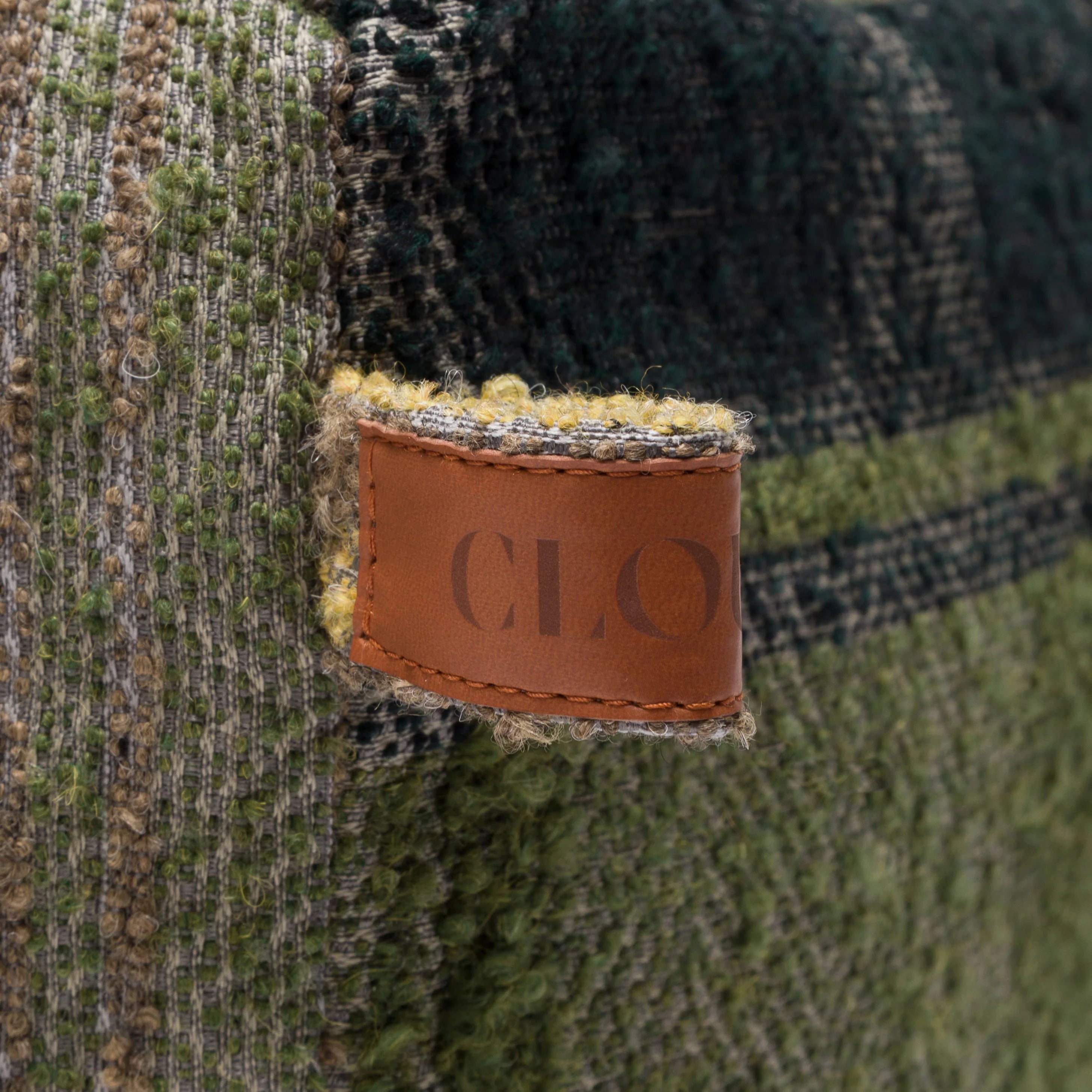 Close-up of a woven fabric with a brown leather label featuring 'CLO'.