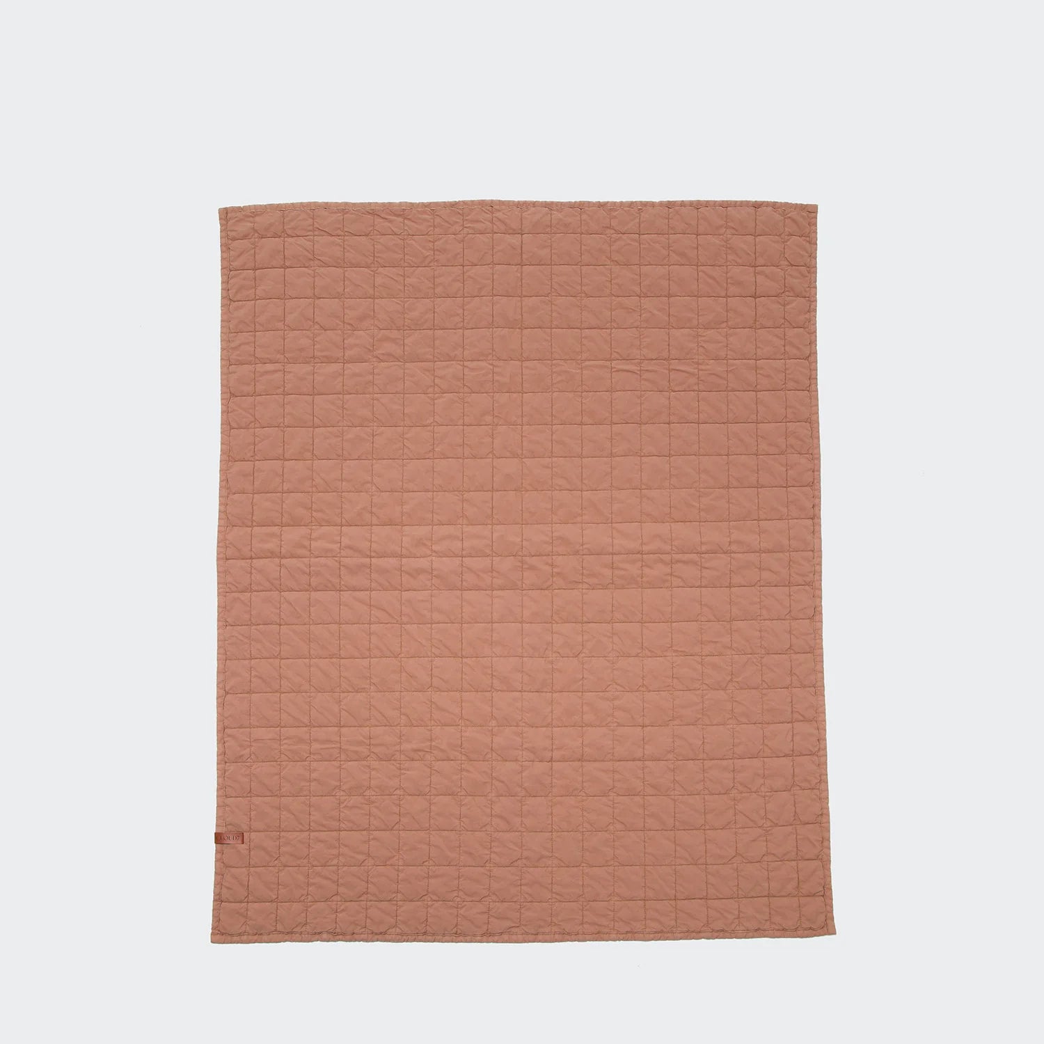 Quilted brown blanket on a light gray background