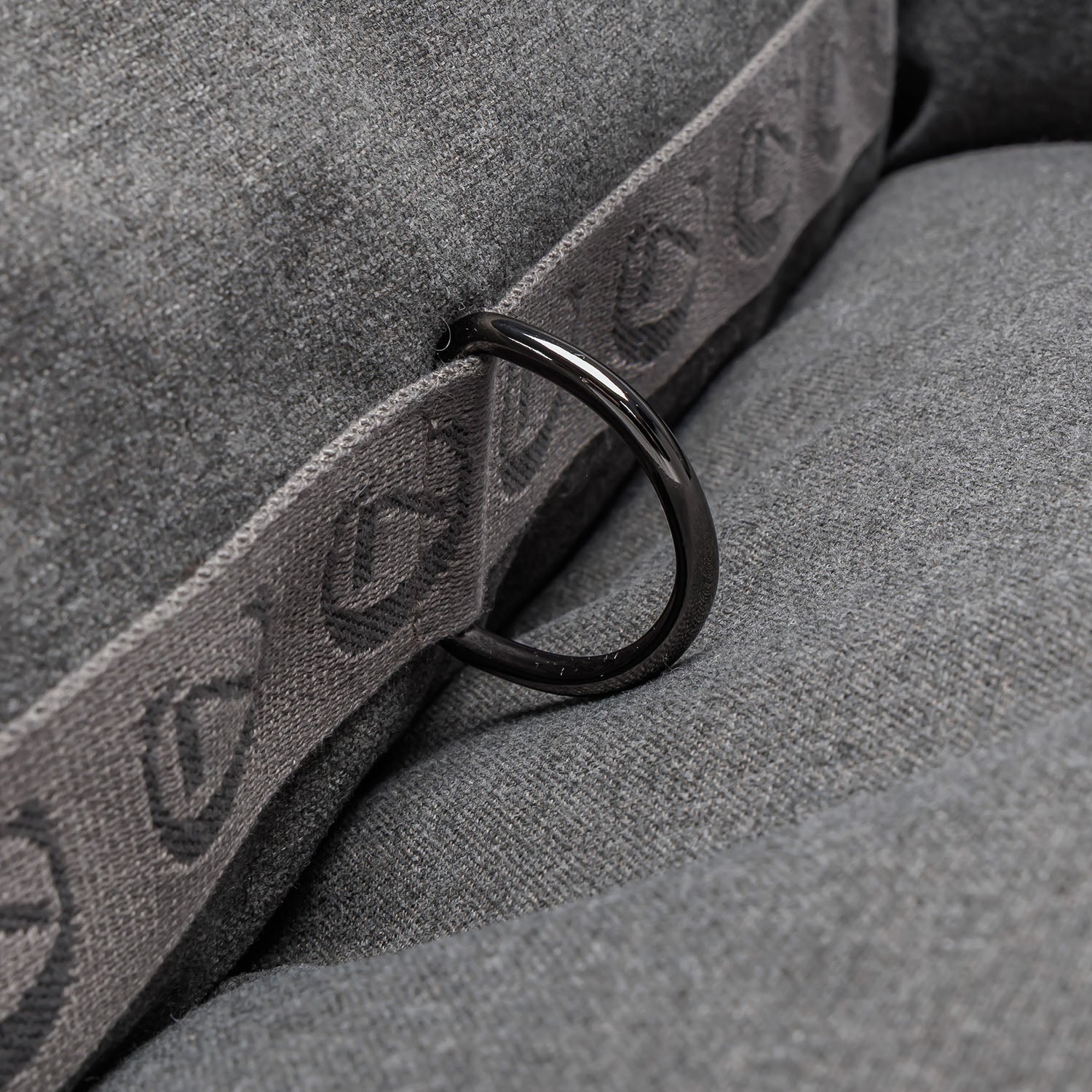 Close-up of a gray strap with a black buckle on a textured gray surface