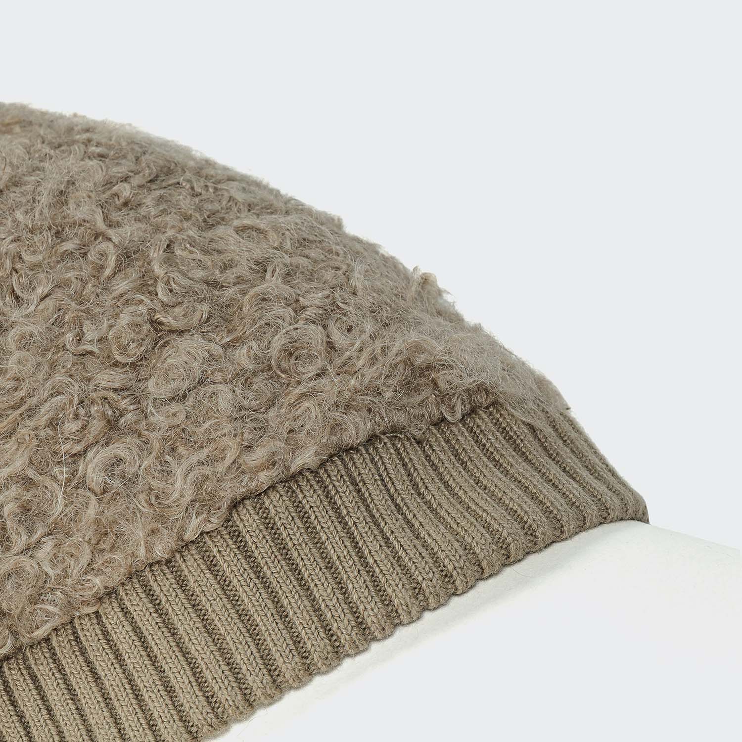 Close-up of a textured beige knit beanie on a white background