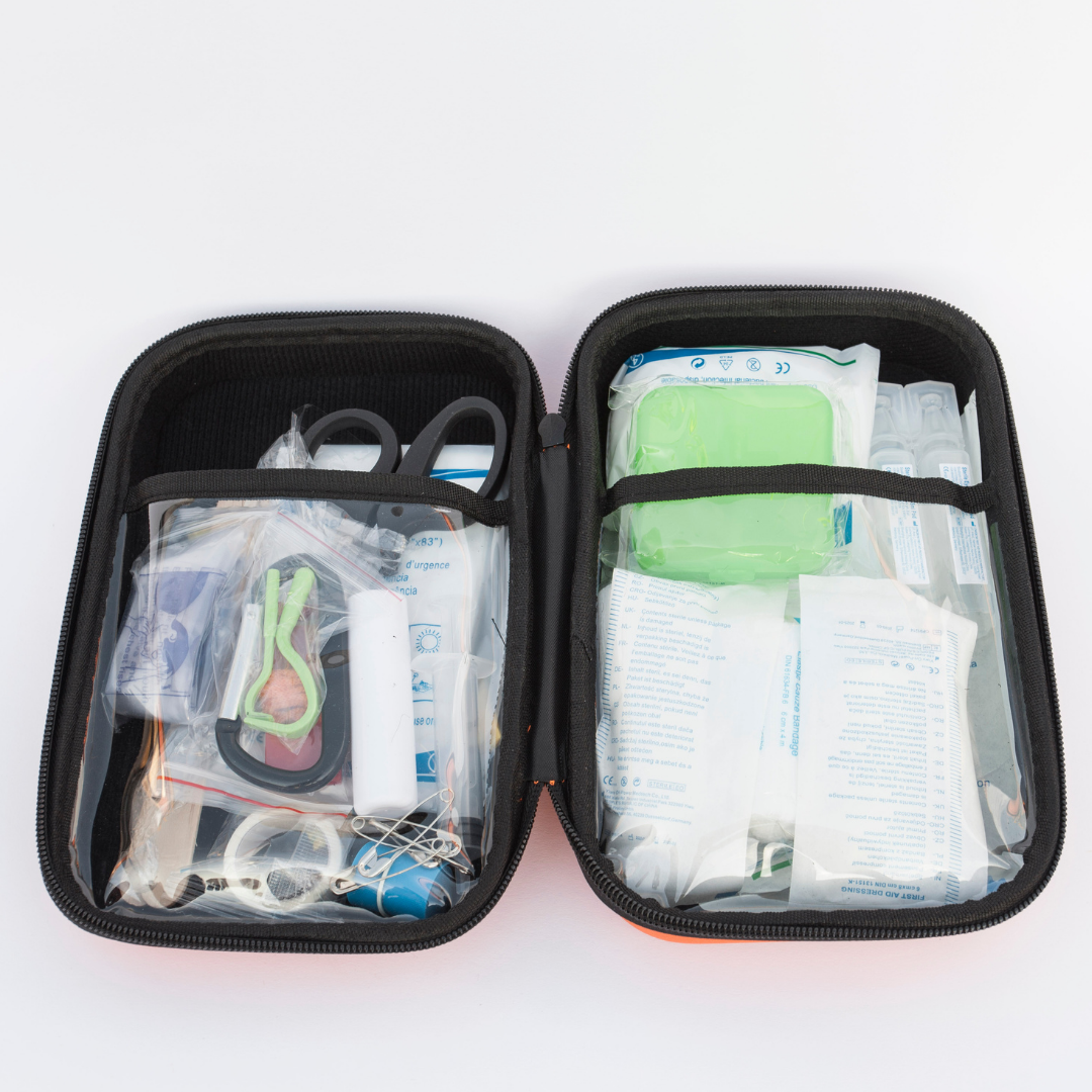 Open first aid kit with various supplies on a white background