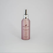 Pink spray bottle with silver nozzle on a light gray background