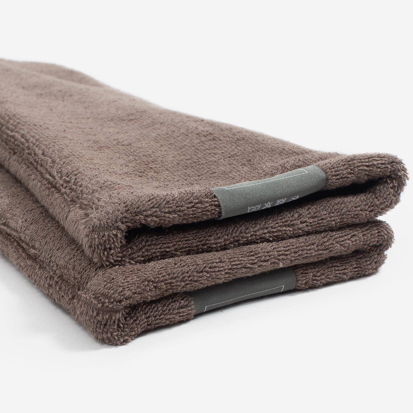 Folded brown towel with a brand label on a white background