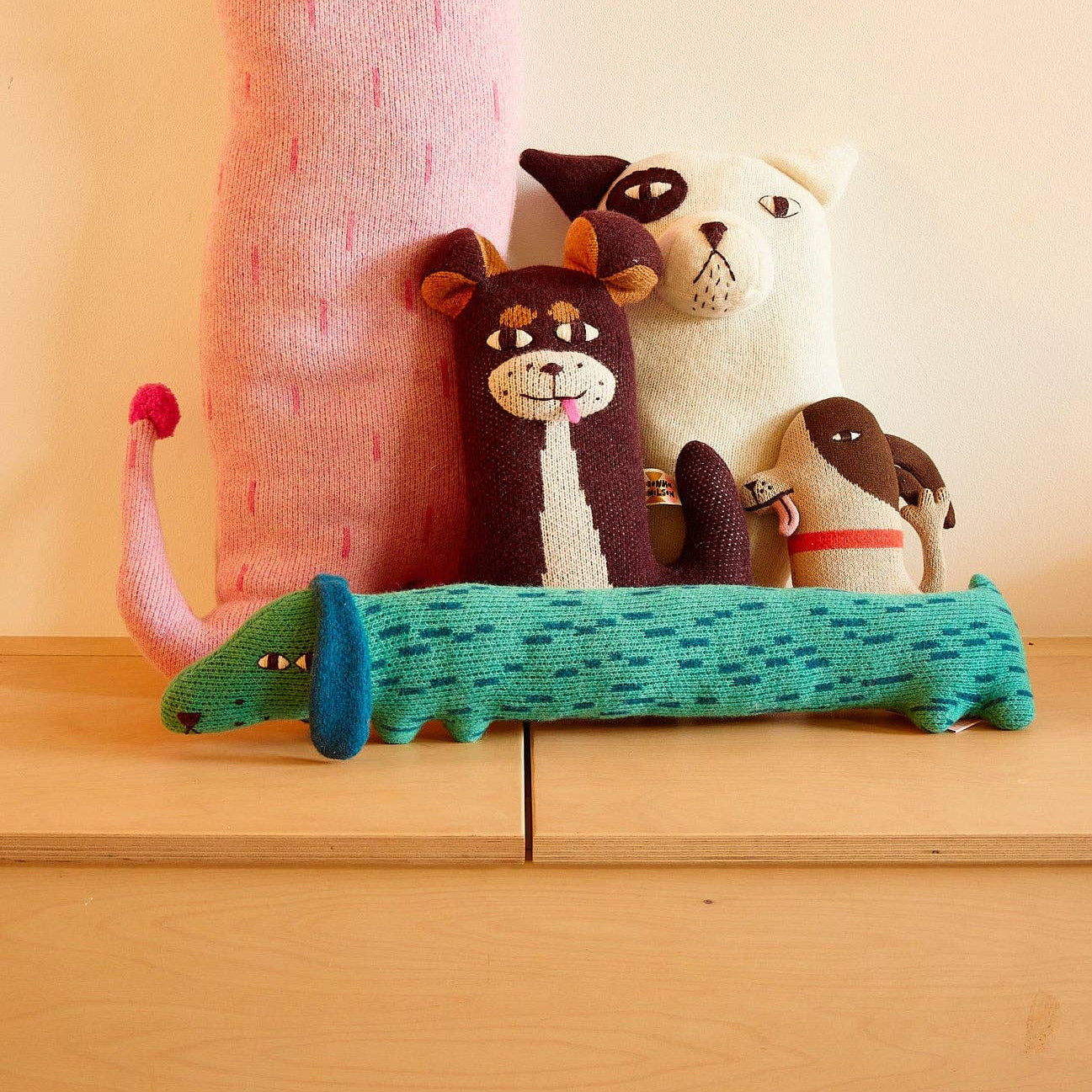 Collection of colorful knitted animals on a wooden surface with a light background