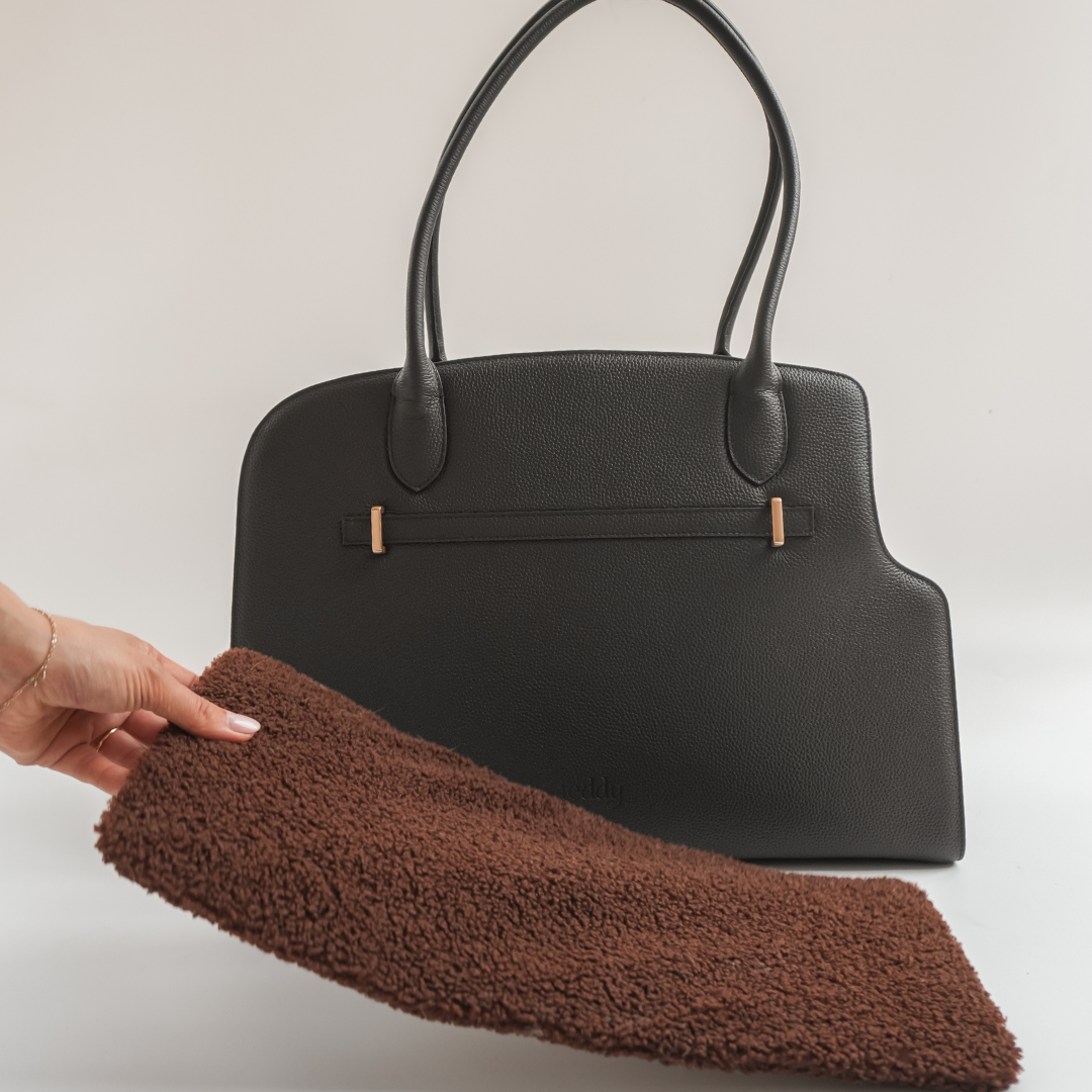 Black handbag with a brown cleaning cloth on a light background