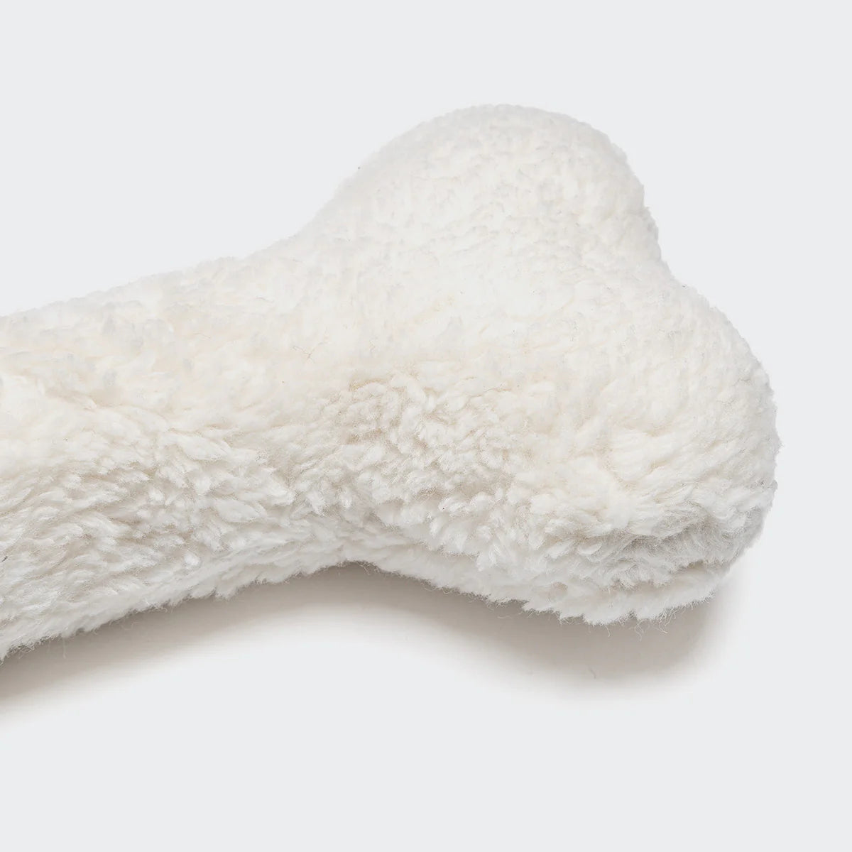 Soft white bone-shaped dog toy made from durable cotton canvas.