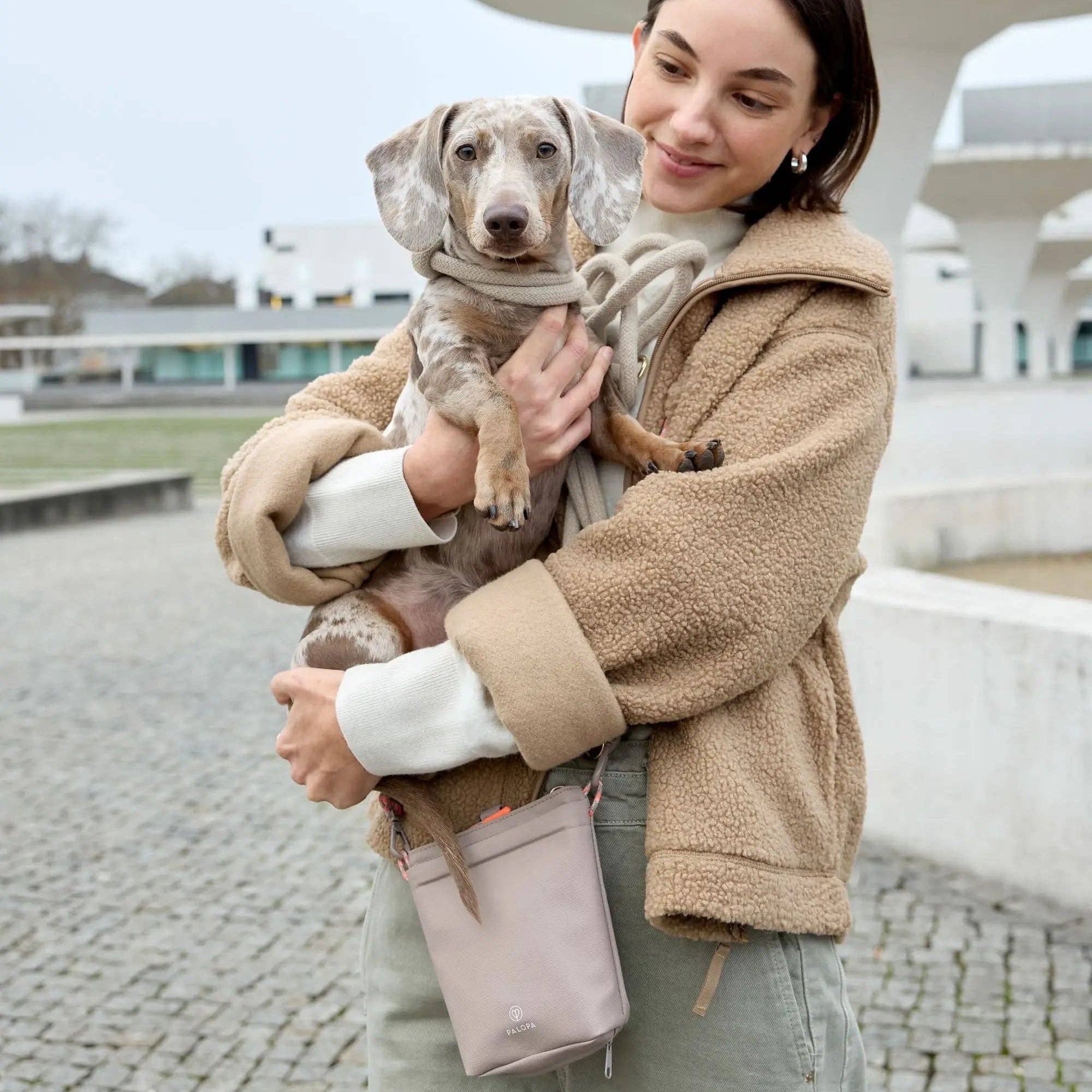 Woman holding a dog outdoors with a building in the background