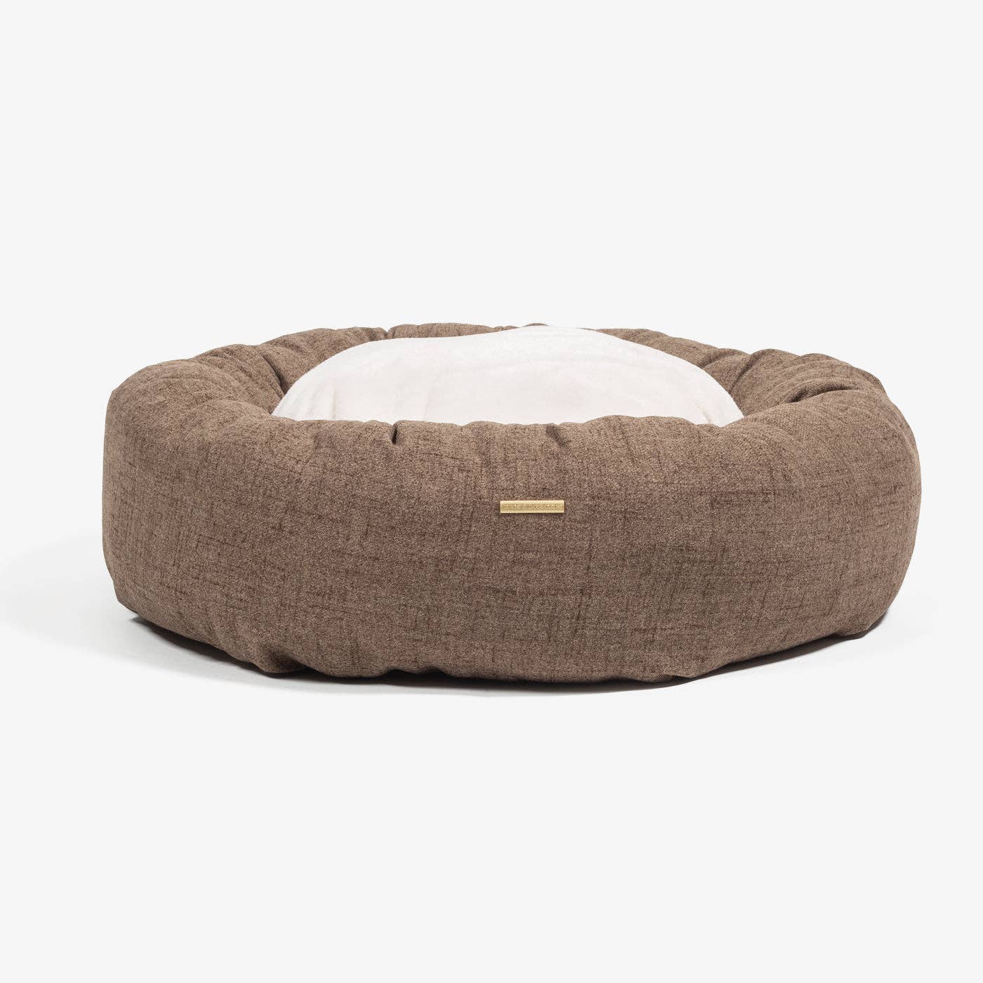 Brown pet bed with a white cushion on a white background