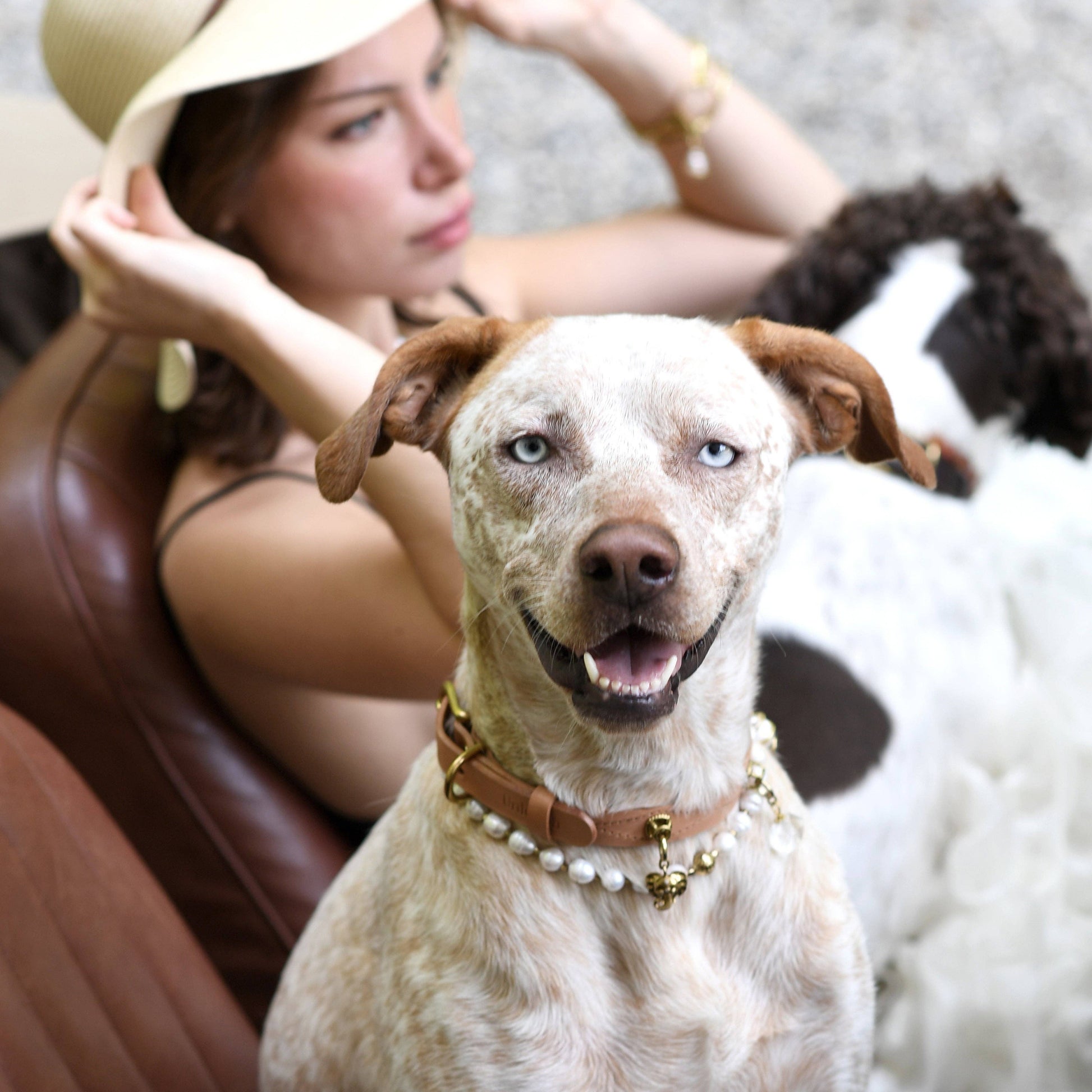 Woman sitting on a couch with a dog wearing a pearl collar