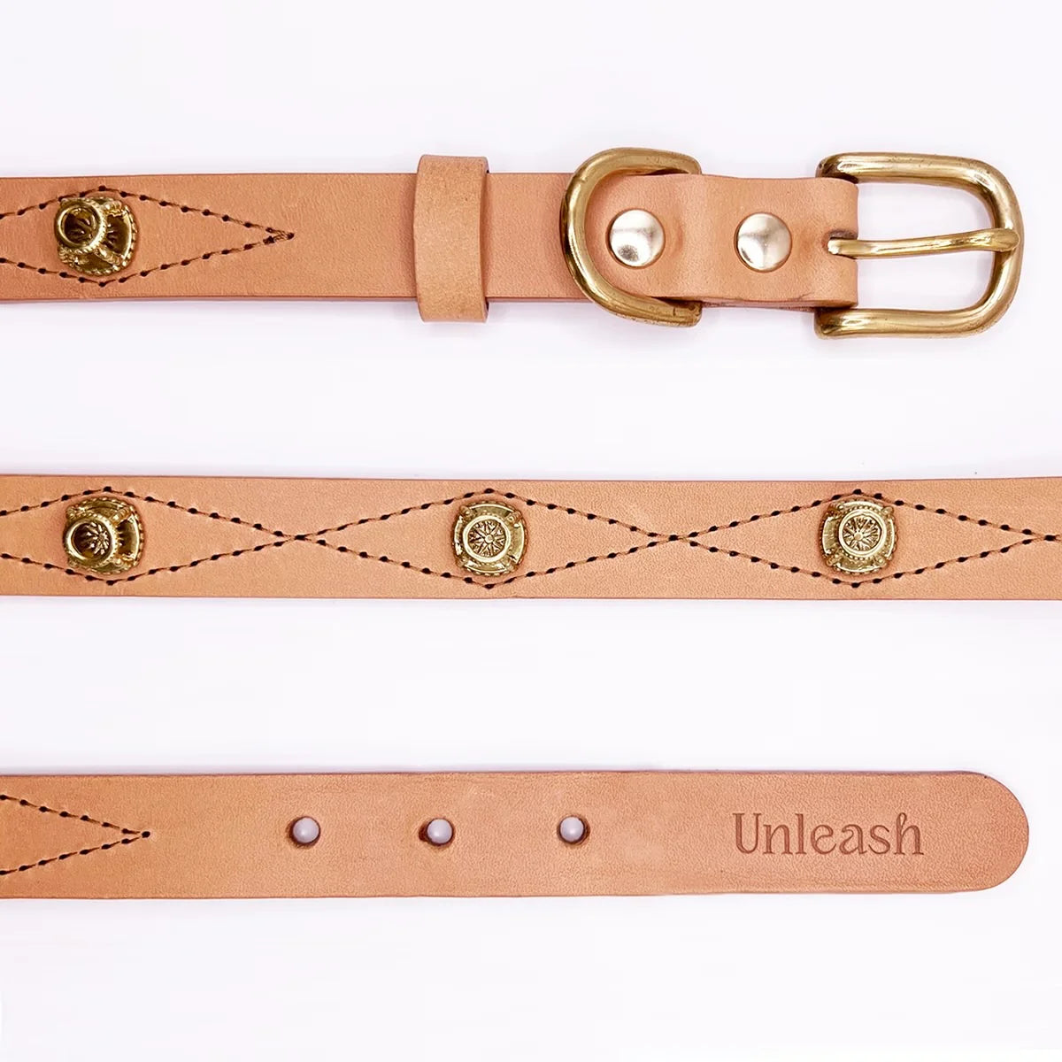 Leather belt with gold hardware and 'Unleash' engraving on a white background