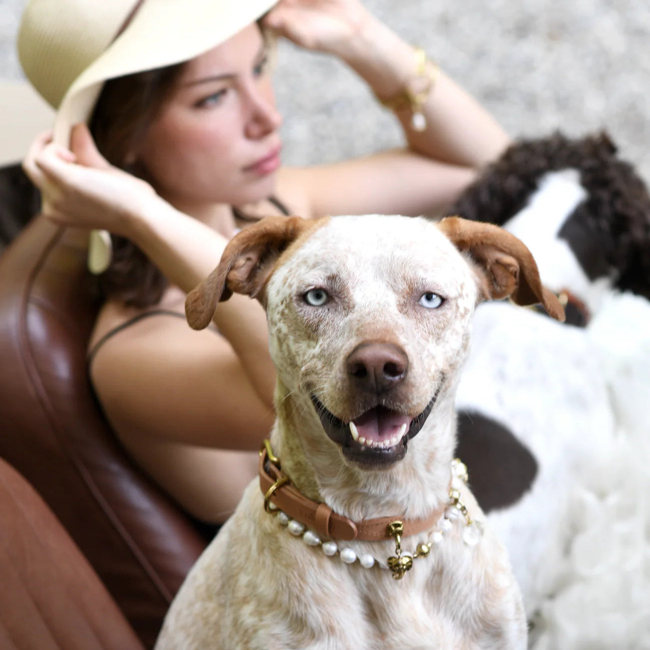 Woman sitting next to a dog wearing a pearl collar