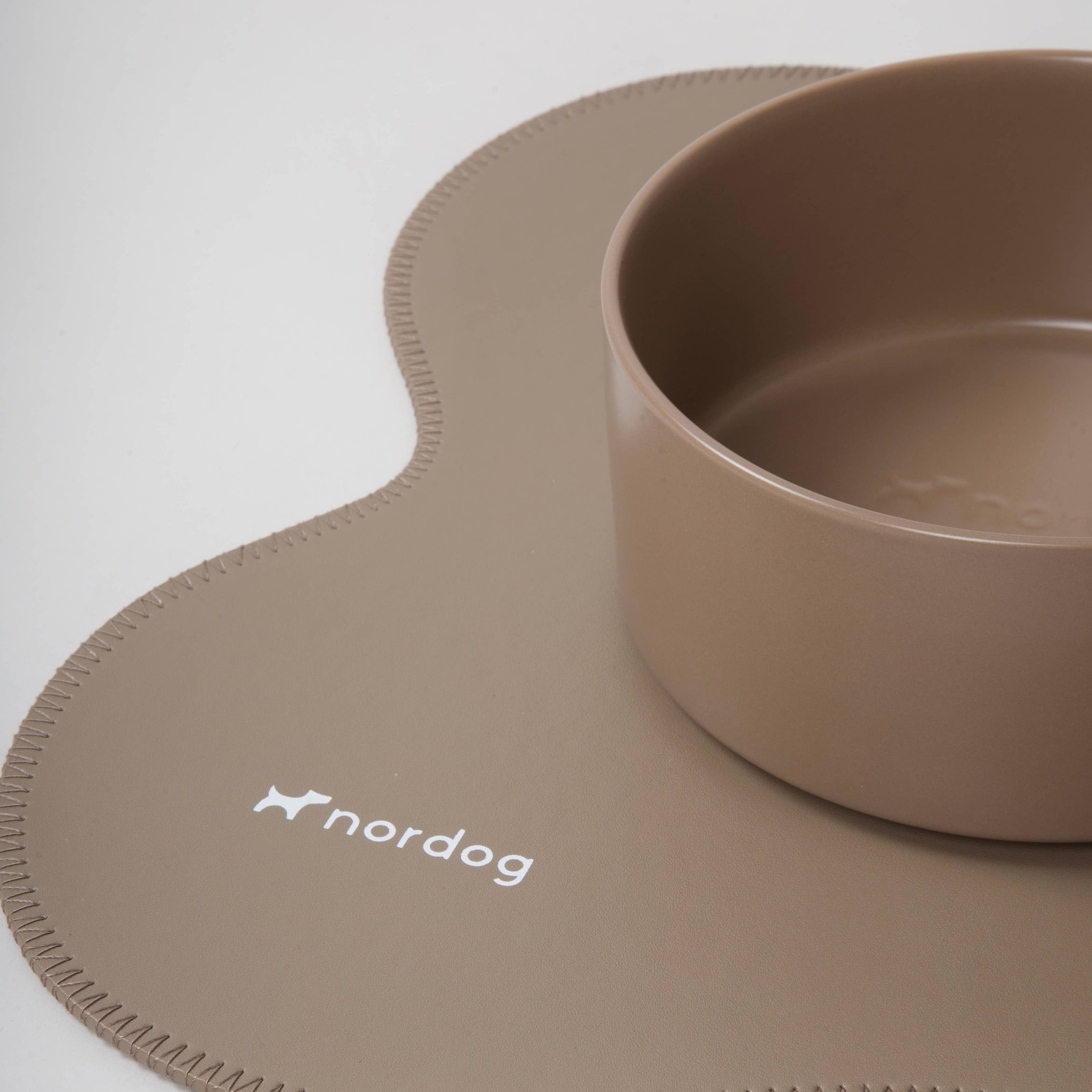 Beige silicone placemat with a bowl on a white background, featuring the 'nordog' brand.