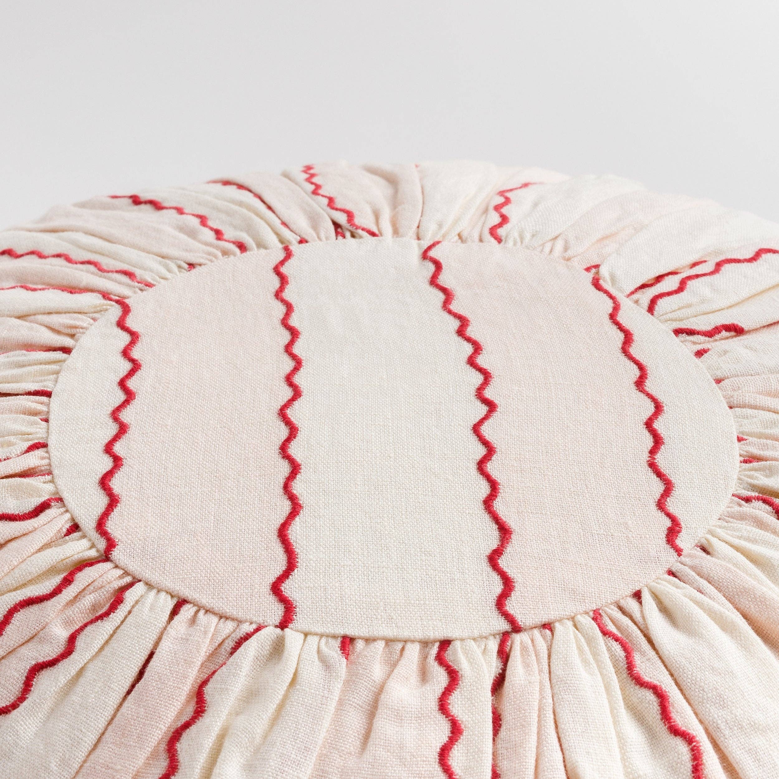 Pink and cream striped round designer cushion with bright red embroidered detailing.