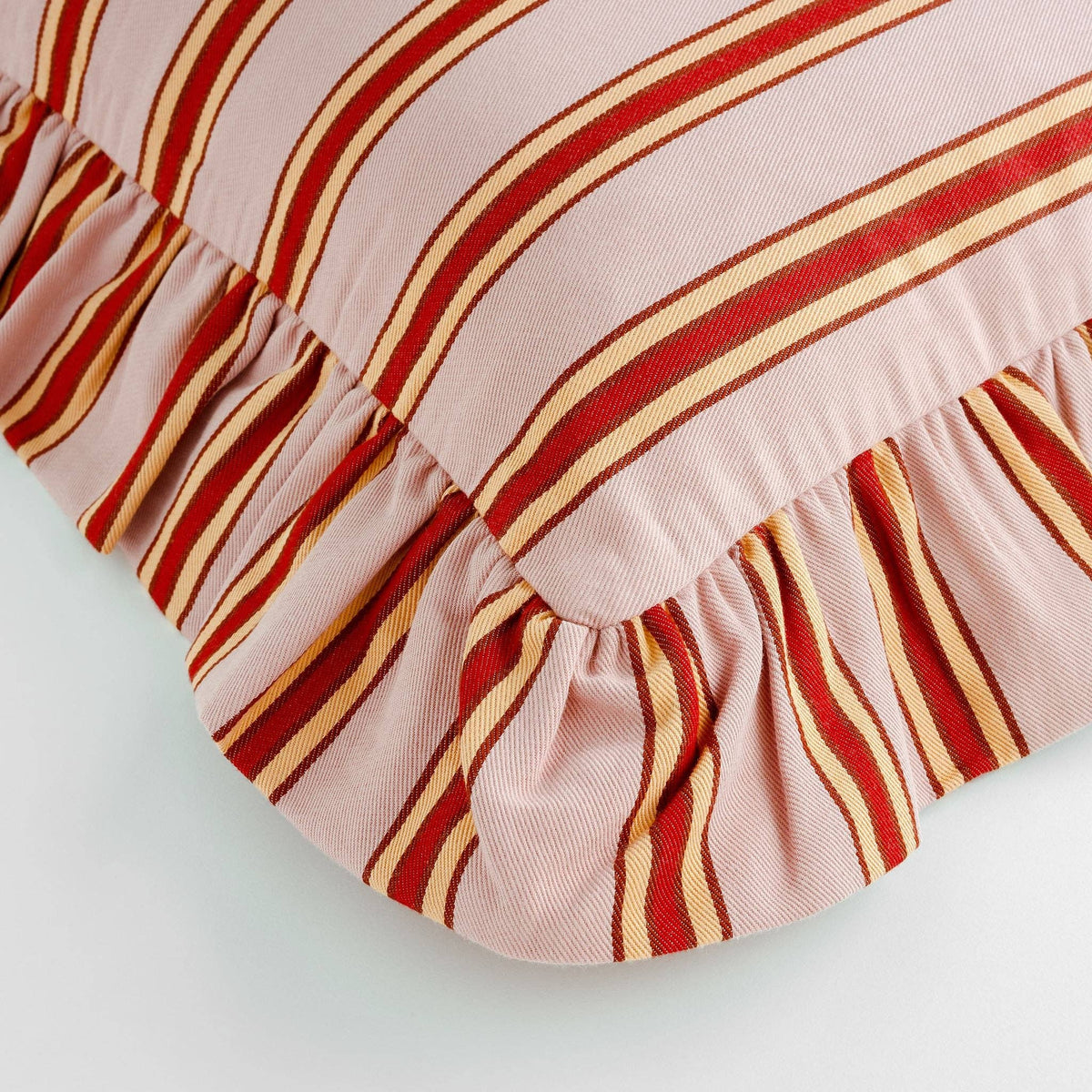Pink striped designer cushion with red, peach and rust stripes and frilled trim.