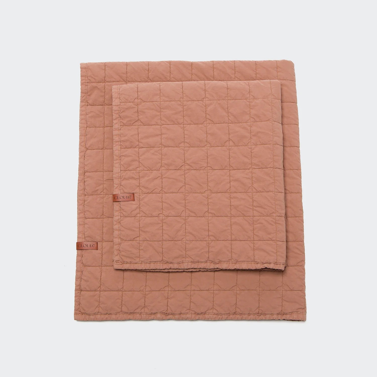 Quilted blanket with a brand label on a light gray background