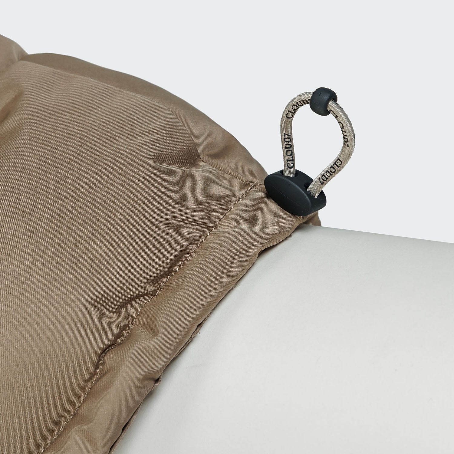 Close-up of a beige tent fabric with a metal carabiner on a white background