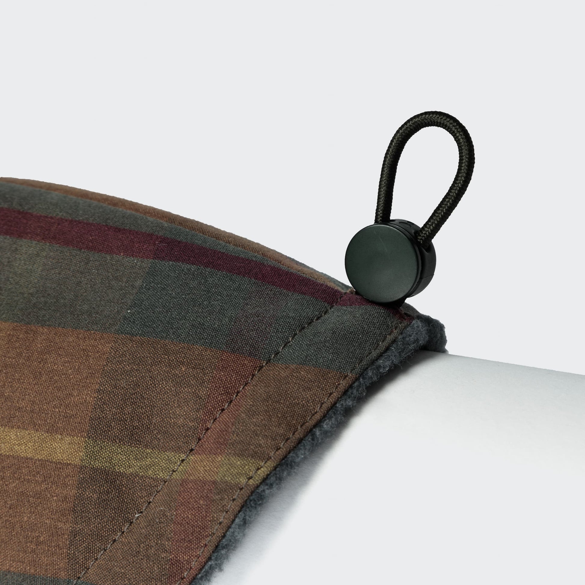 Close-up of a plaid fabric with a black zipper pull on a white background