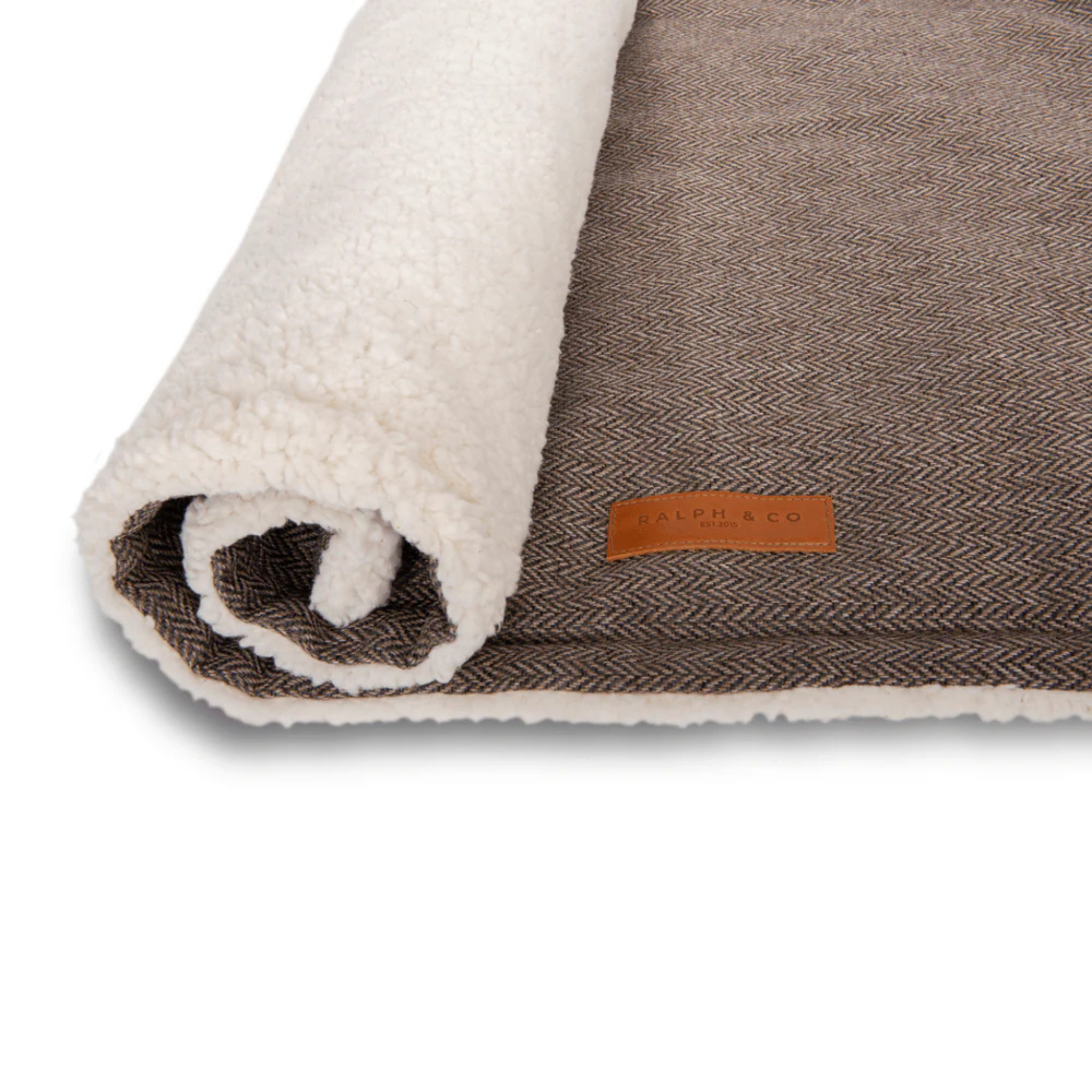 Brown textured blanket with white fleece edge and brand label on a white background