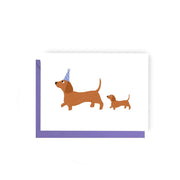 Illustration of two dogs, one wearing a party hat, on a white background with a purple border.