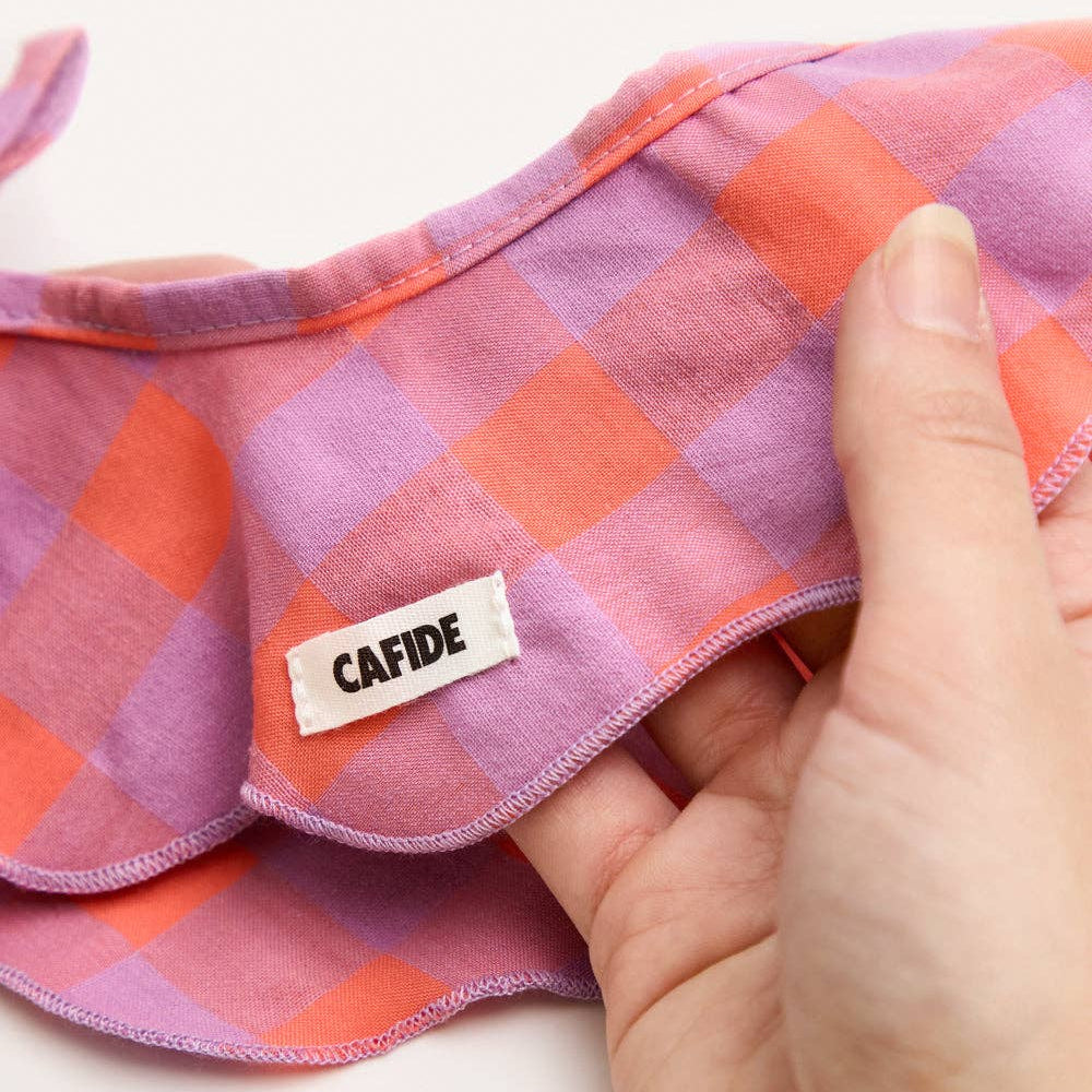Checkered fabric with a 'CAFIDE' label held by a hand on a white background