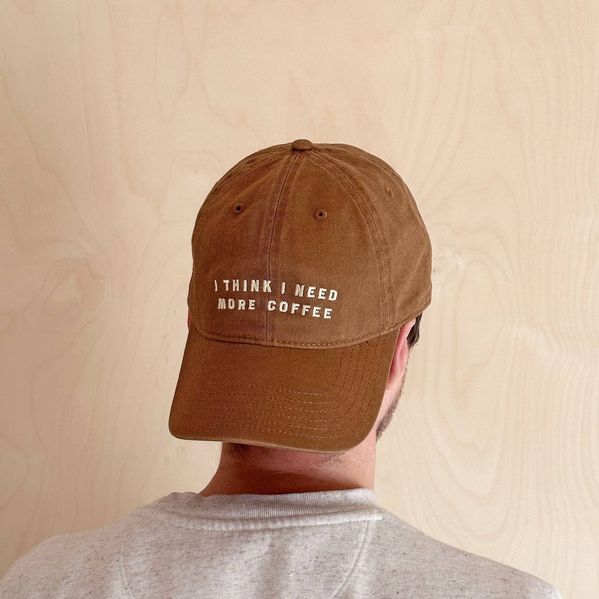 Tan brown cotton baseball cap with off-white embroidered coffee slogan.