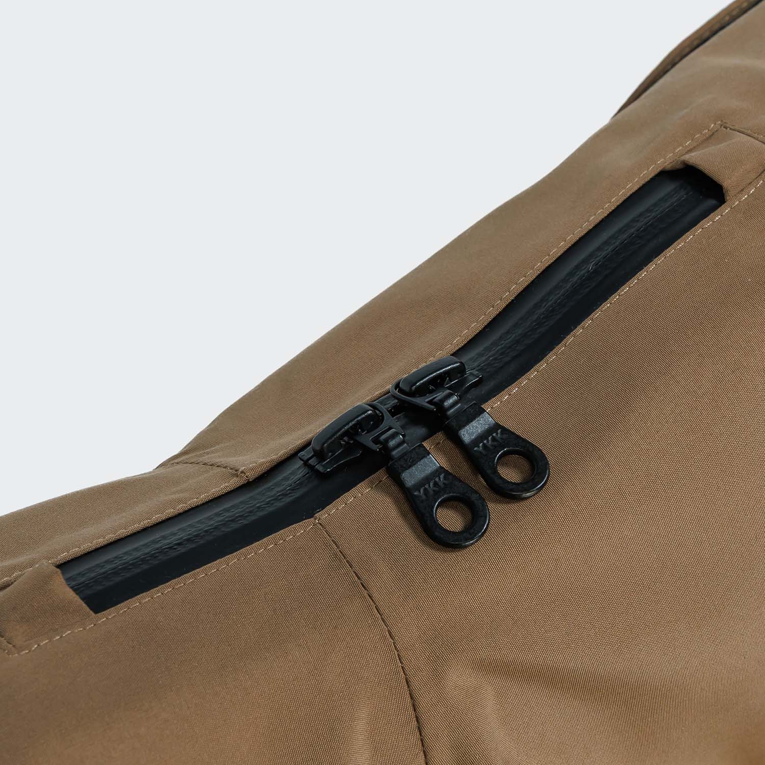 Close-up of a brown bag with a black zipper on a light gray background