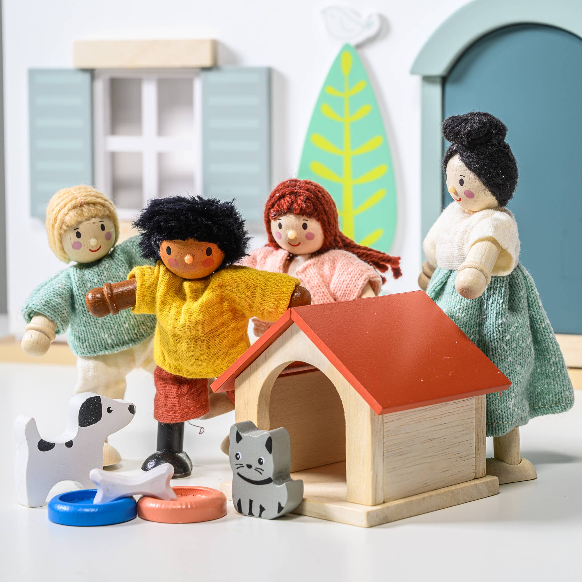 Toy figures of a family with a doghouse and pets on a white background