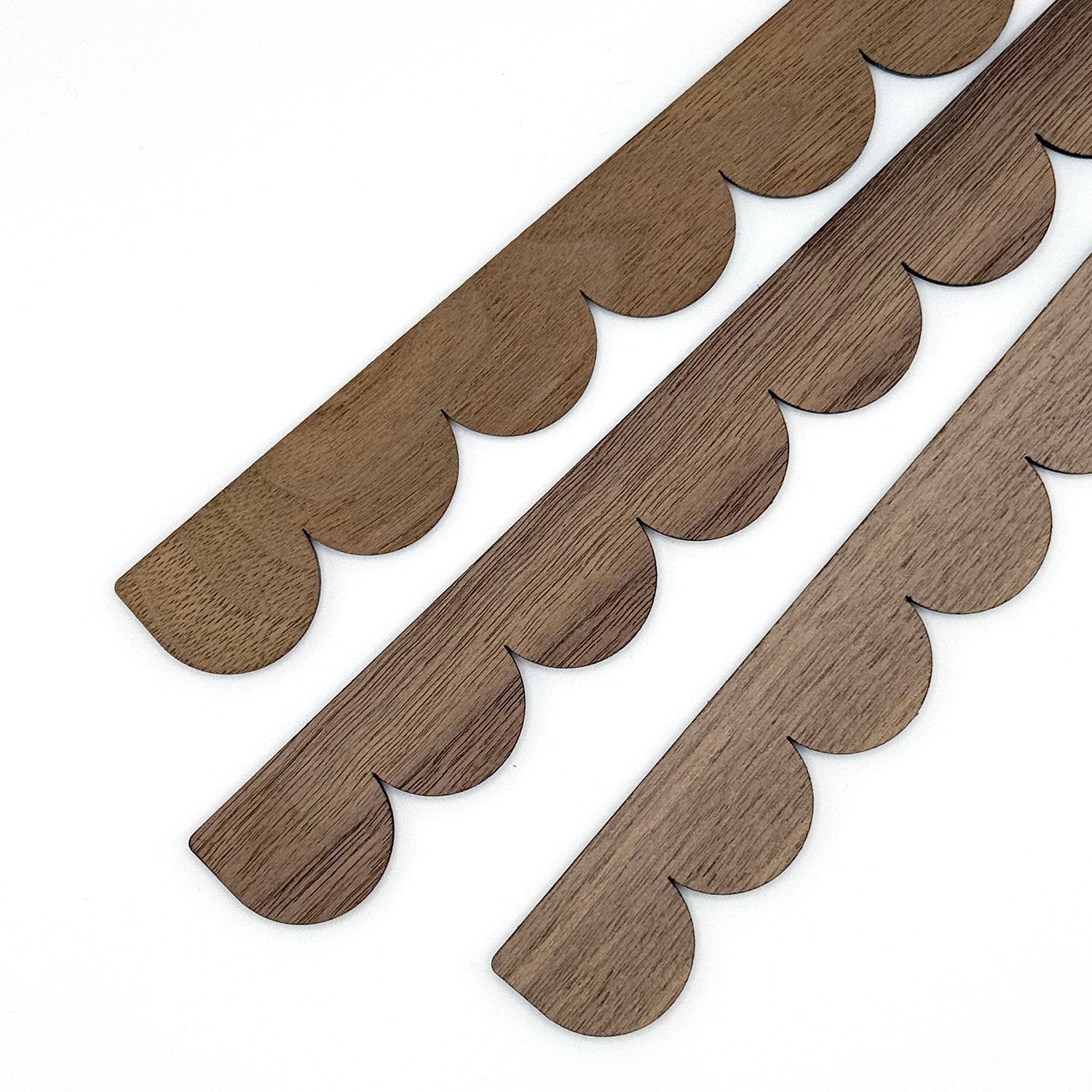 Wooden decorative trim pieces with scalloped edge on a white background