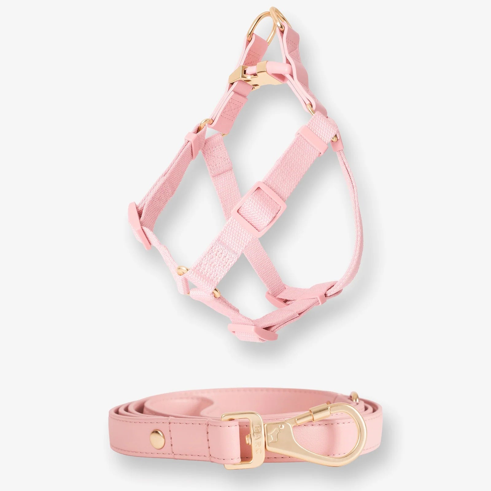 Pink dog harness and leash set with gold hardware on a white background