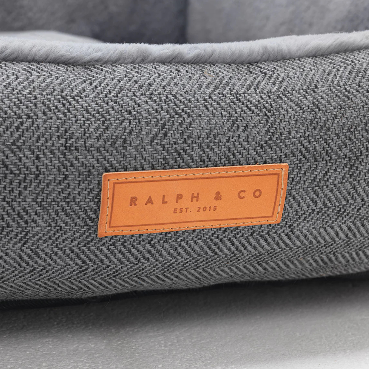 Gray textured pet bed with a brand label on a white background