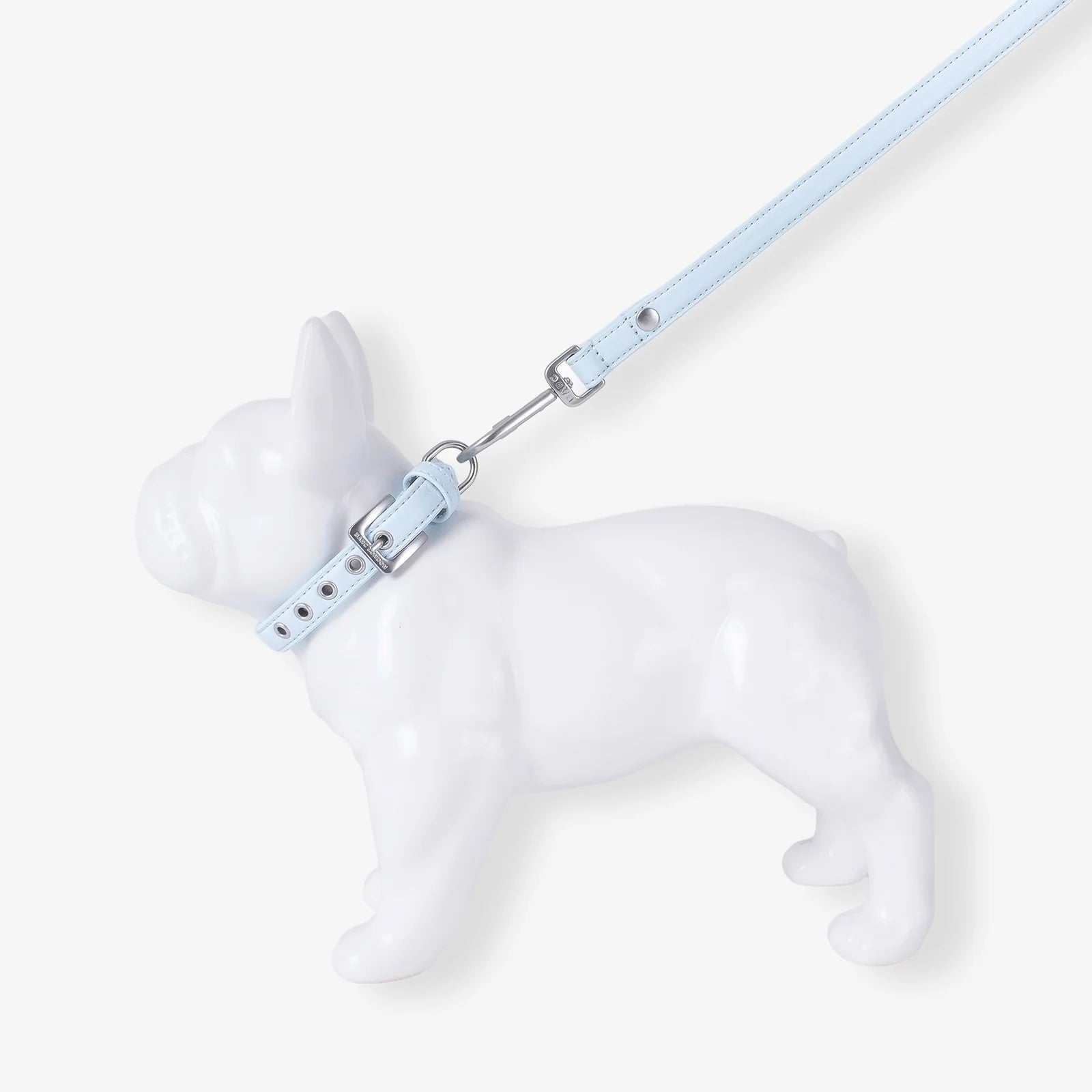 White dog figurine with a light blue leash on a white background