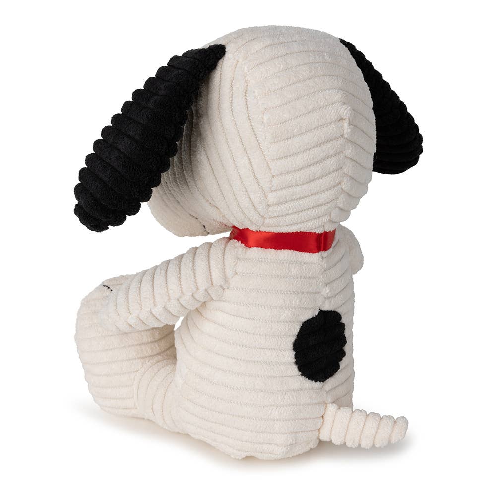 Stuffed dog toy with black ears and paws, wearing a red ribbon on a white background