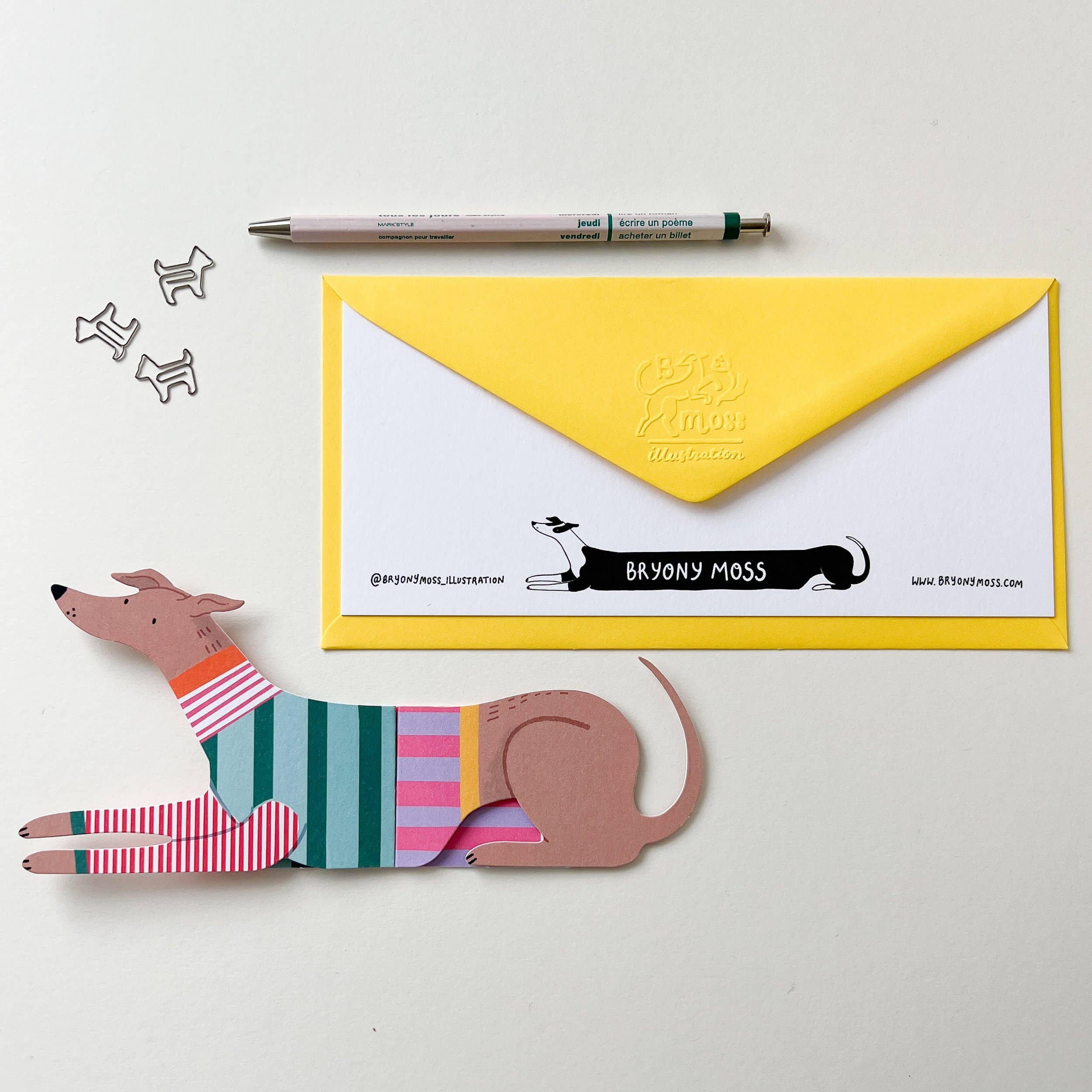 Dog-shaped letter opener with a yellow envelope and pen on a white background